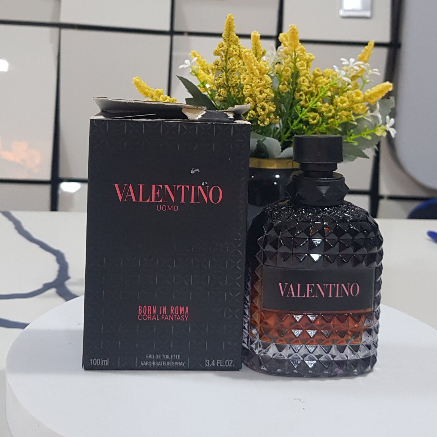 Vektor perfume bottle and packaging on a table with a decorative plate in the background.