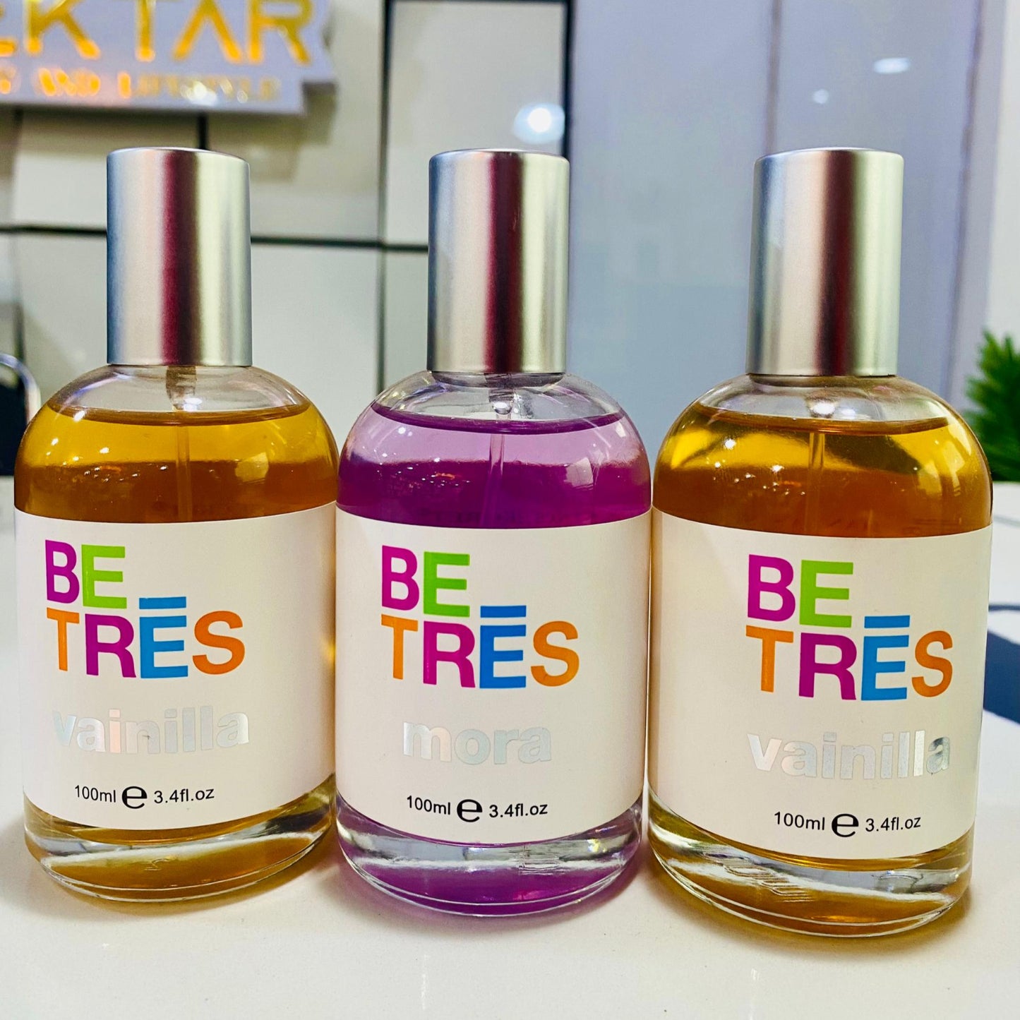 Three 'BETRES' perfume bottles with colorful labels on a white surface.