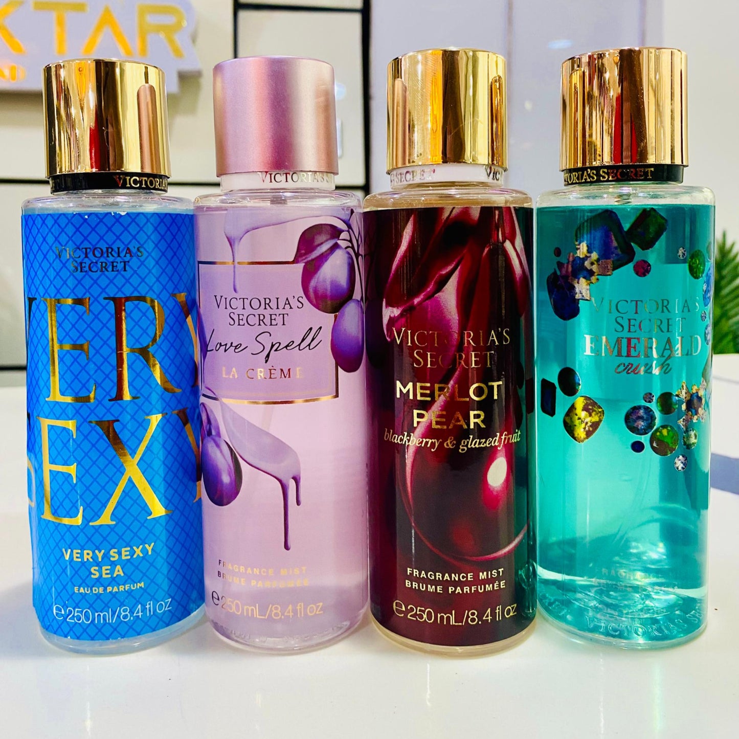 Four Victoria's Secret fragrances bottles on a white surface with a blurred background.