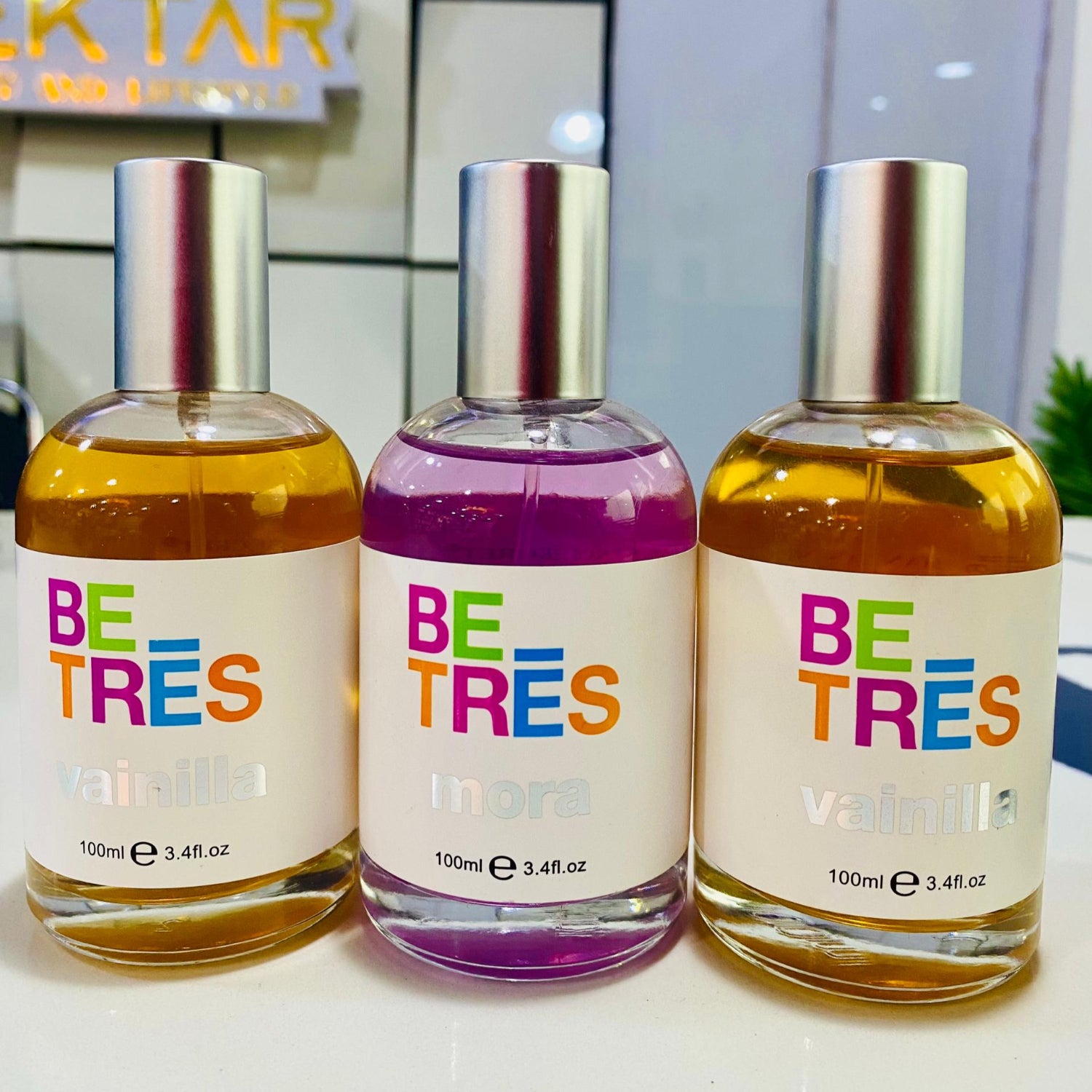 Three 'BETRES' perfume bottles with colorful labels on a white surface.