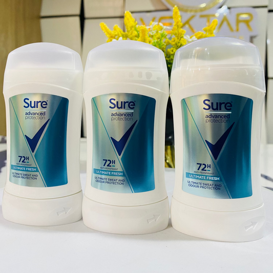 Three Sure deodorant sticks on a white surface with a blurred background featuring a logo.