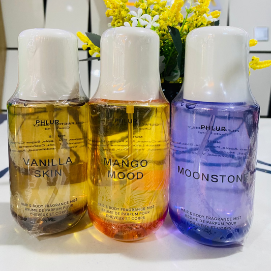 Three bottles of perfume labeled 'Vanilla Skin', 'Mango Mood', and 'Moonstone' on a white surface with a decorative background.