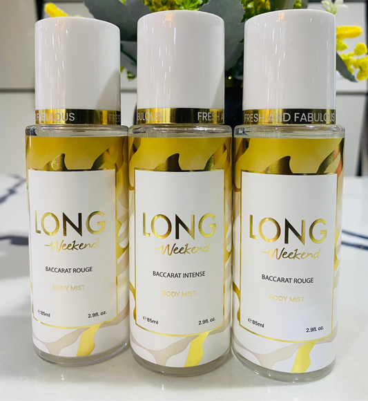 Three bottles of 'LONG Weekend' perfume with floral arrangement in the background