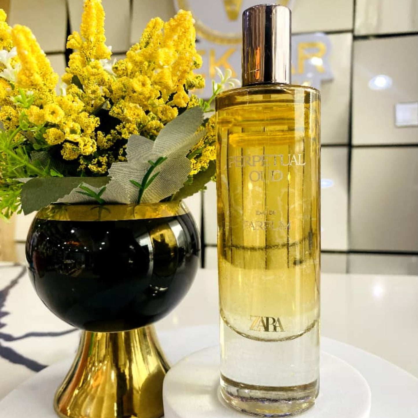 Perfume bottle with yellow flowers on a white surface