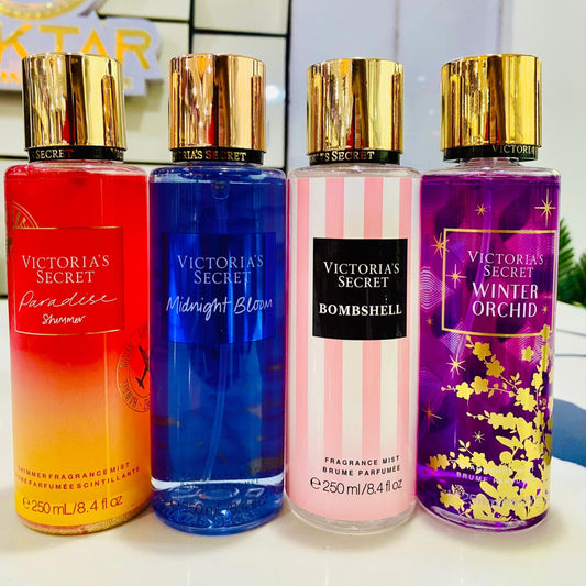 Four Victoria's Secret fragrances bottles in different colors on a white surface.